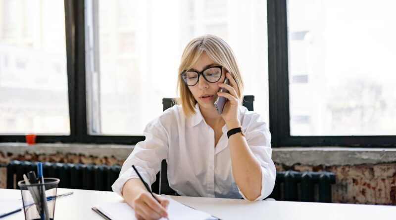 a woman writing down notes while having a phone call